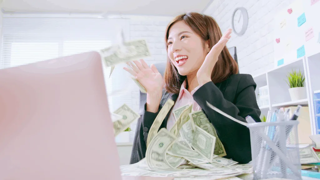 A creator celebrating online income at her desk, symbolizing financial success made possible through the evolving creator economy in 2026.